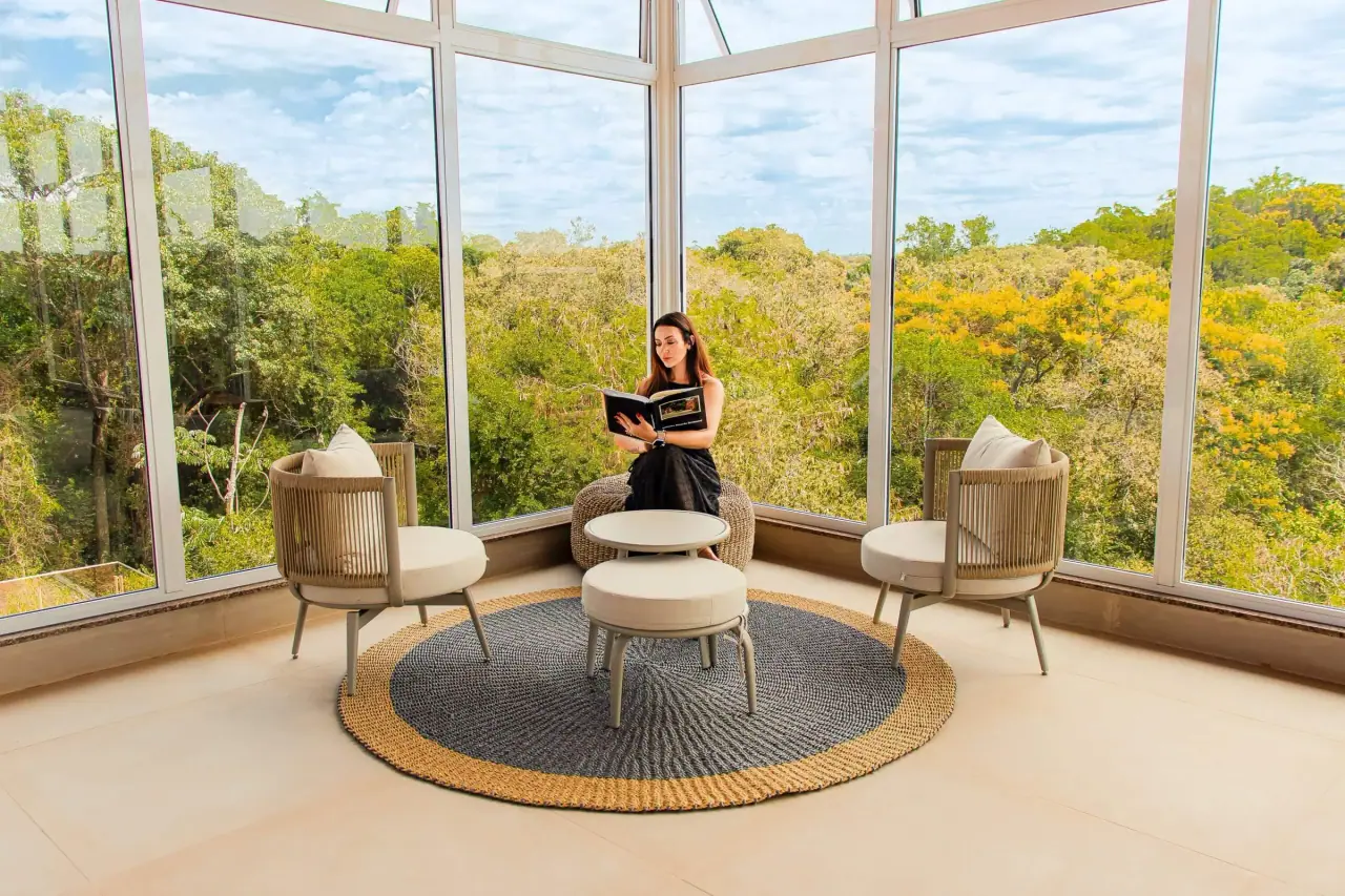 Glass-walled lookout with armchairs and a view of the trees