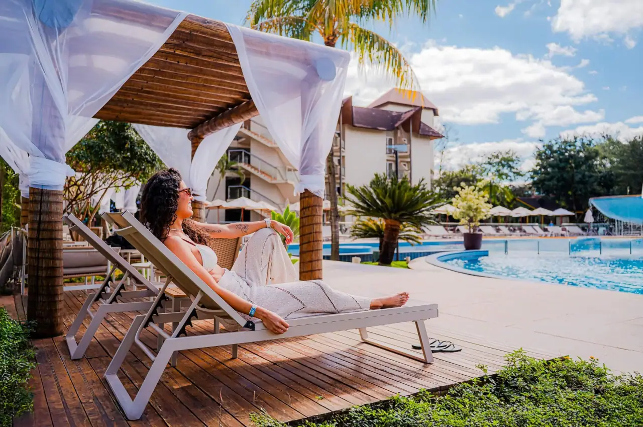 Hóspede relaxando em espreguiçadeira ao lado da piscina termal do Recanto Cataratas