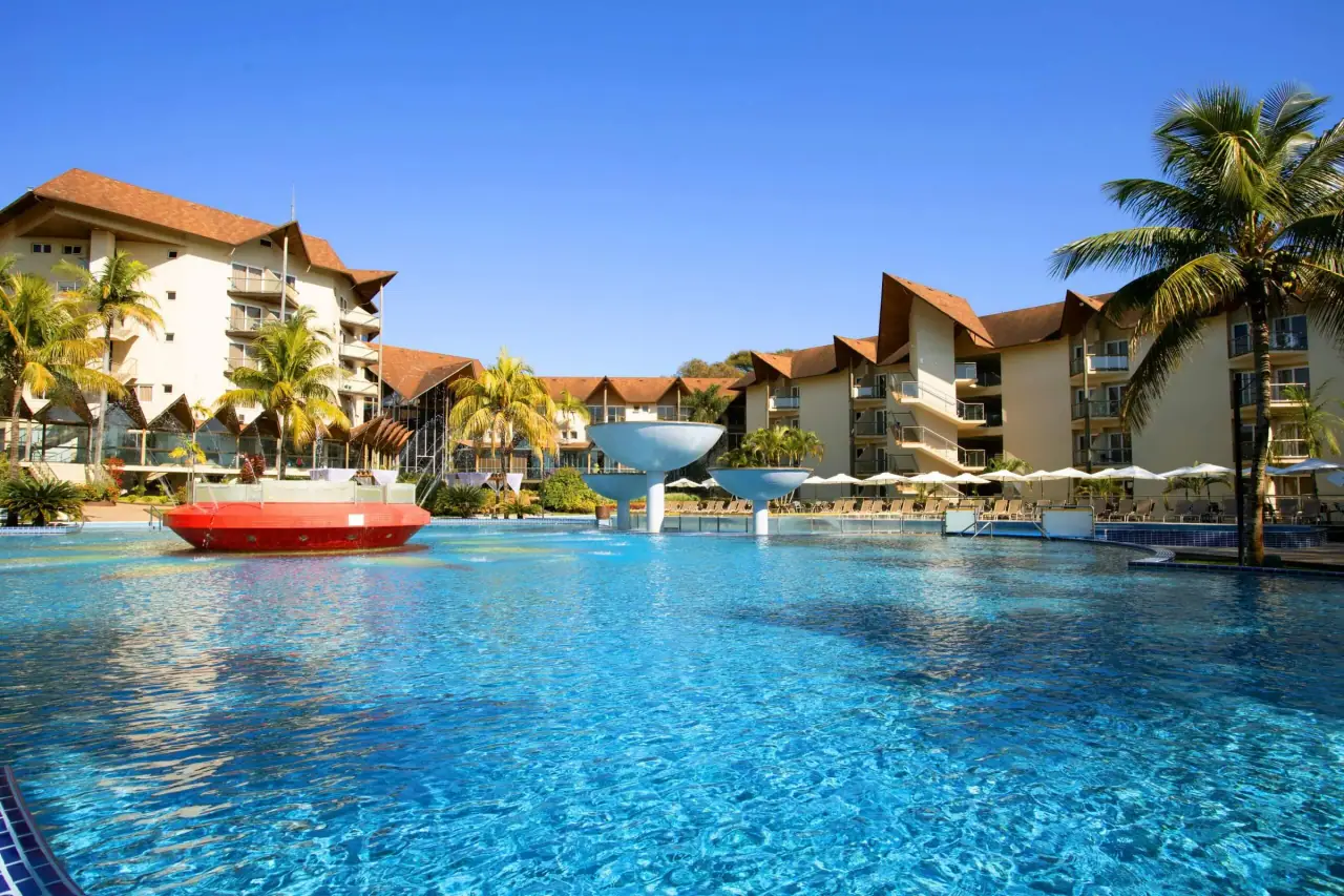 Outdoor thermal pool under a blue sky, with the resort behind
