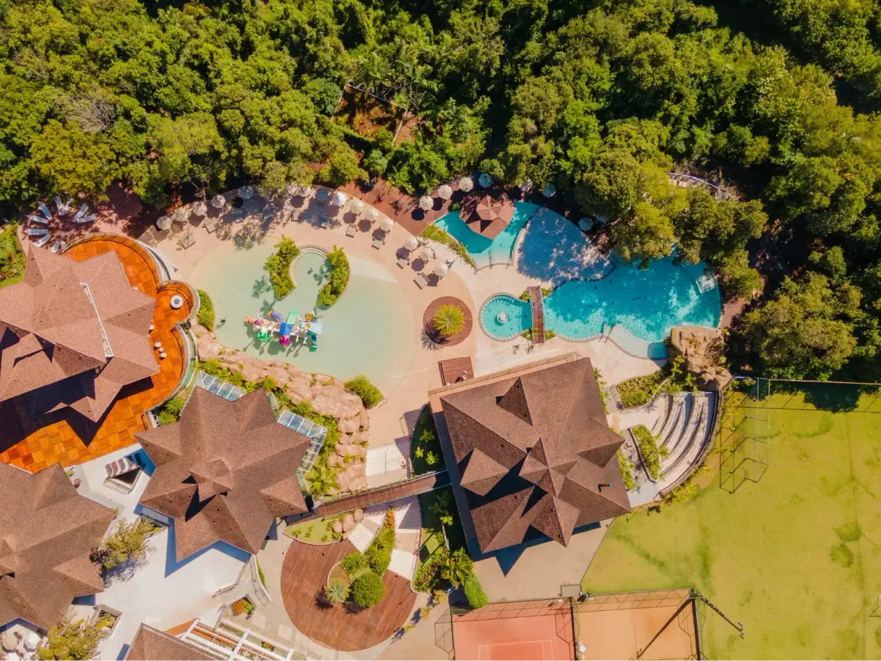 El resort visto desde arriba, con techos, piscinas y árboles alrededor